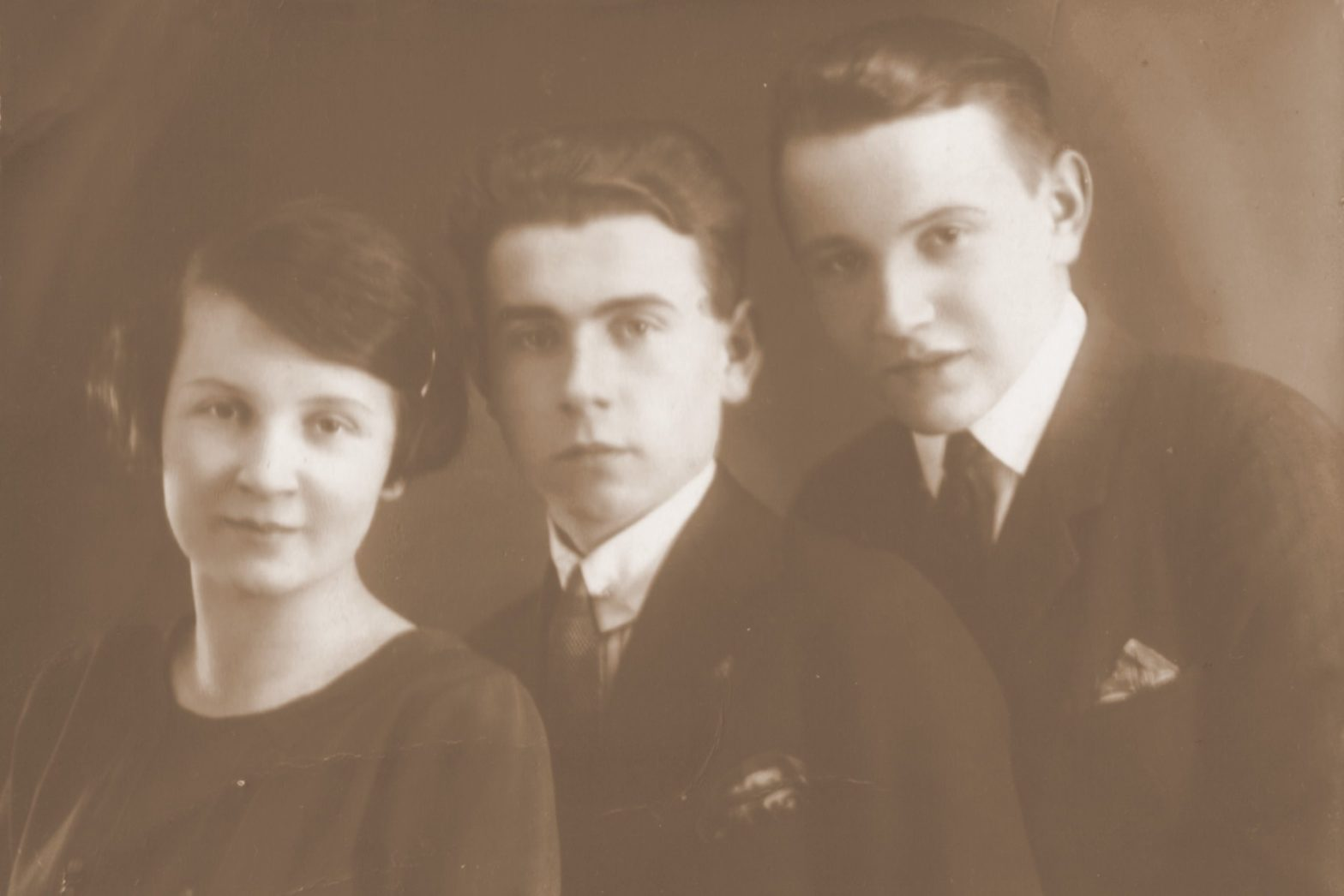 Fotografia w sepii. Portret młodej kobiety i dwóch młodych mężczyzn elegancko ubranych.