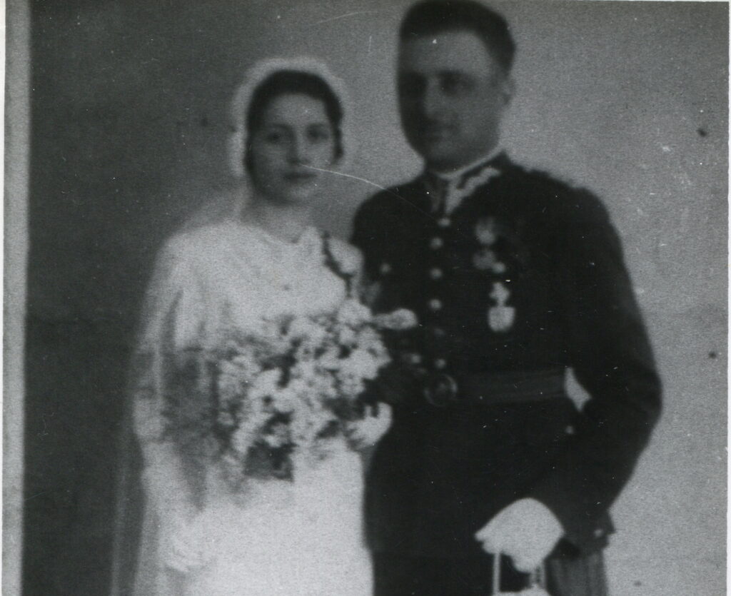 Zdjęcie czarno-białe, ślubne, kobieta w białej sukni, w welonie, z bukietem kwiatów i mężczyzna w mundurze Wojska Polskiego.