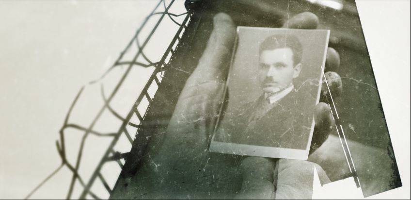 Ręce trzymające fotografię - portret mężczyzny w garniturze.