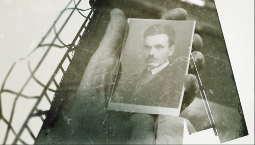 Ręce trzymające fotografię mężczyzny w garniturze.