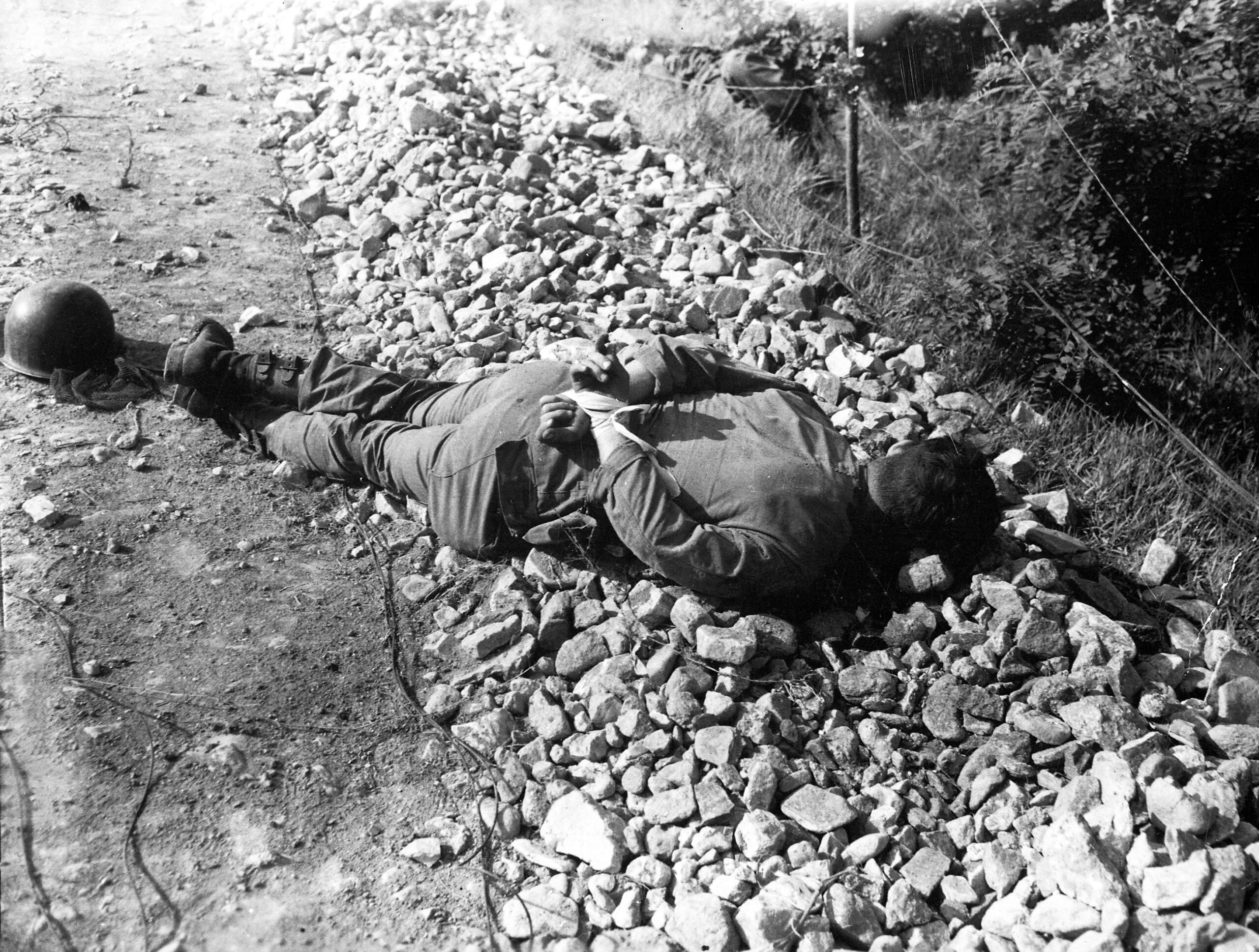 Na zdjęciu martwy amerykański jeniec wojenny leżący ze skrępowanymi rękami, zastrzelony strzałem w tył głowy przez chińskich lub koreańskich komunistów, Korea 1950