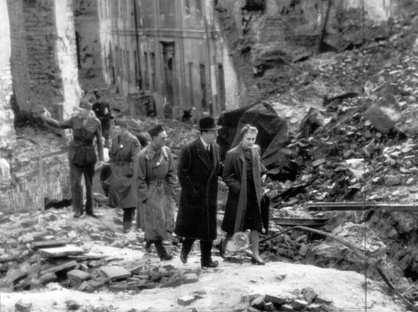 Na zdjęciu Ambasador USA w Polsce, Arthur Bliss-Lane w ruinach Warszawy, 1945 rok Ambasador idzie pod rękę z kobietą, prawdopodobnie żoną pośród ruin miasta. Za nimi grupa kilku żołnierzy amerykańskich.