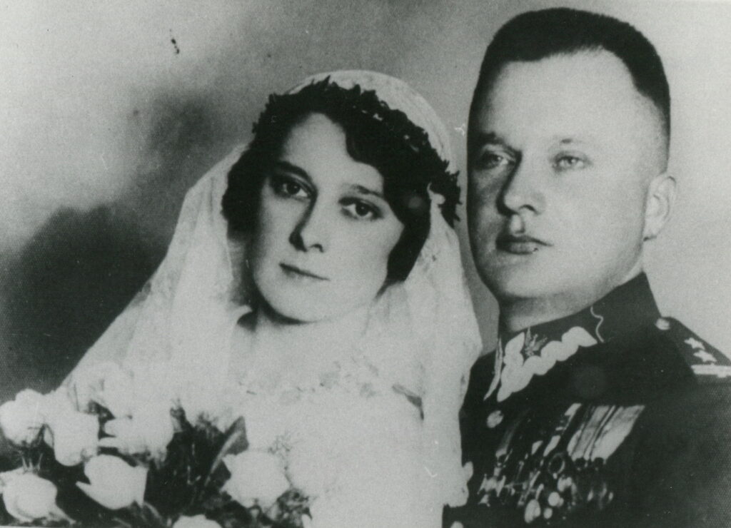 Czarno-białe zdjęcie ślubne, kobieta w welonie, trzyma bukiet kwiatów, mężczyzna w munudrze Wojska Polskiego.